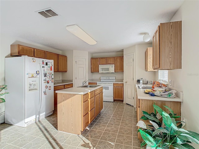 kitchen with sink, white appliances, and an island with sink