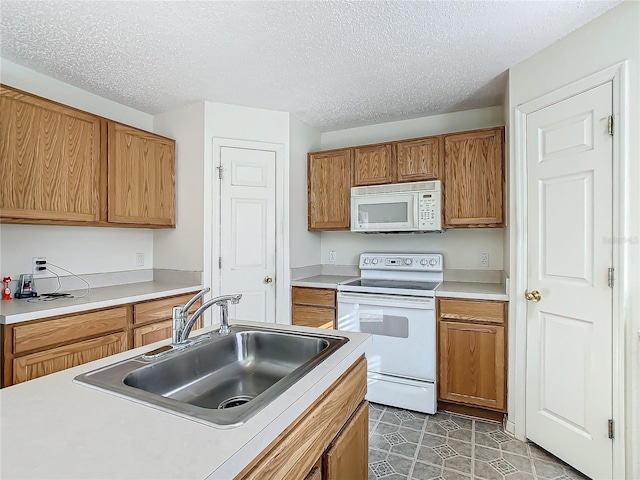 kitchen with tile patterned flooring, a textured ceiling, white appliances, and sink