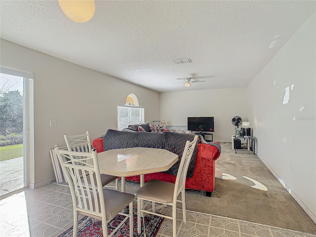 carpeted dining area with ceiling fan and a textured ceiling