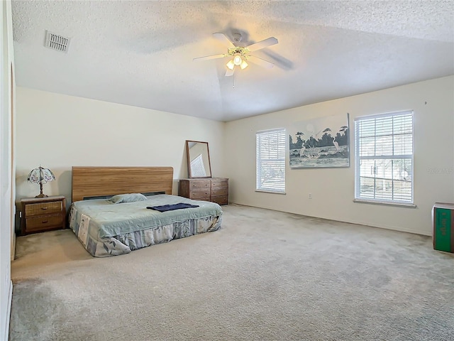 carpeted bedroom with ceiling fan and a textured ceiling