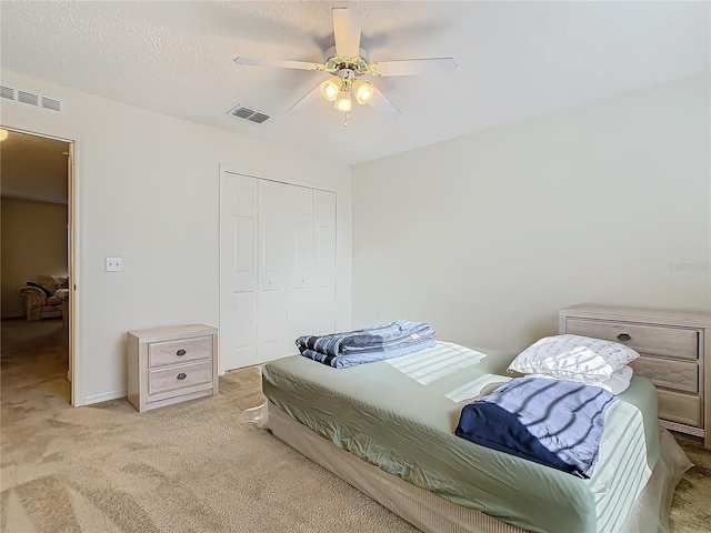 carpeted bedroom featuring ceiling fan, a textured ceiling, and a closet