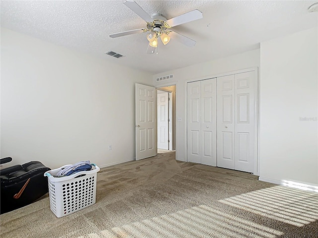 bedroom featuring ceiling fan, carpet floors, a textured ceiling, and a closet