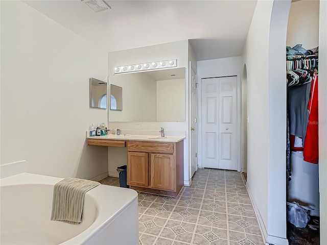 bathroom with tile patterned flooring, vanity, and a tub to relax in