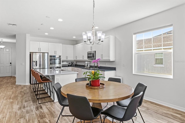 dining area with a notable chandelier, light hardwood / wood-style floors, and sink