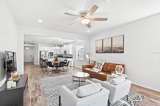 living room featuring ceiling fan and light hardwood / wood-style floors