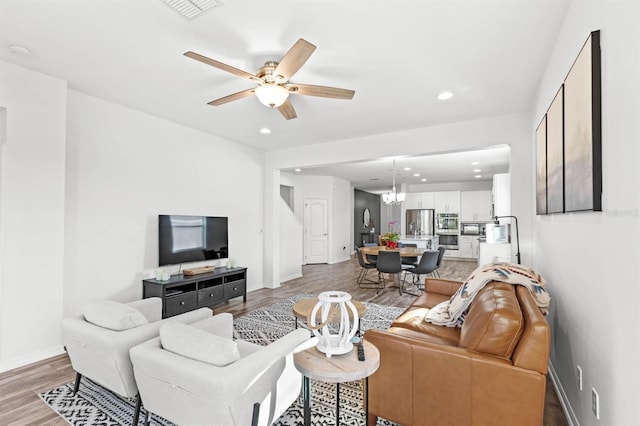 living room with hardwood / wood-style floors and ceiling fan with notable chandelier