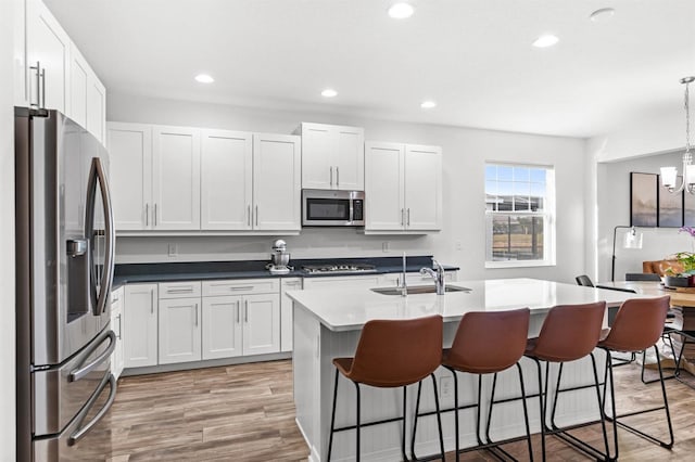 kitchen with hanging light fixtures, white cabinetry, sink, and stainless steel appliances