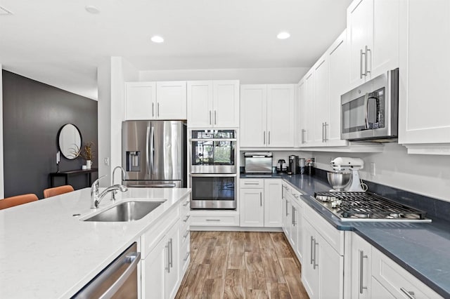 kitchen featuring white cabinets, light hardwood / wood-style floors, sink, and appliances with stainless steel finishes