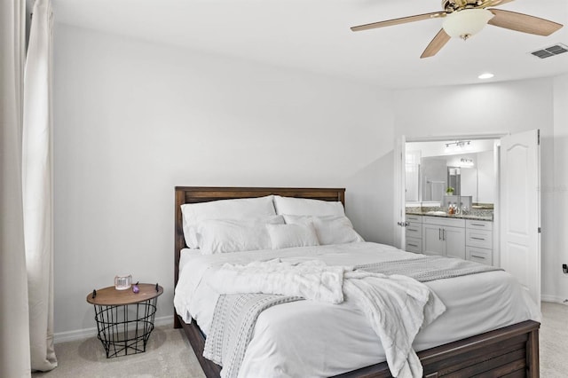 carpeted bedroom with ensuite bath and ceiling fan