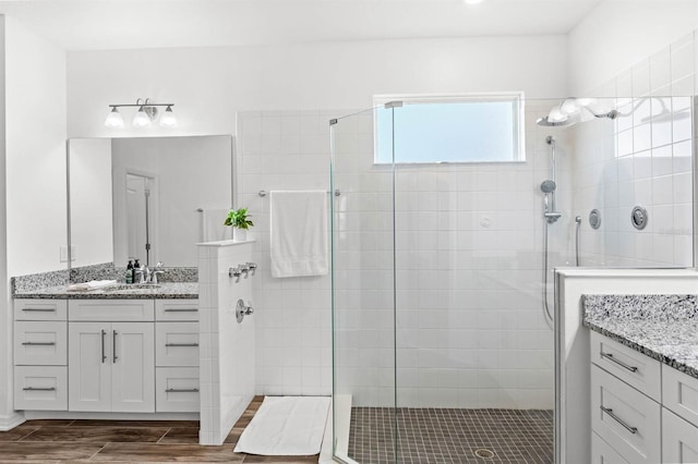 bathroom with a tile shower and vanity