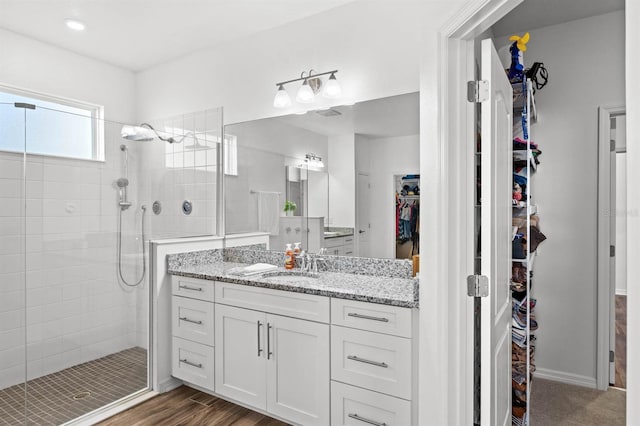 bathroom with a tile shower and vanity