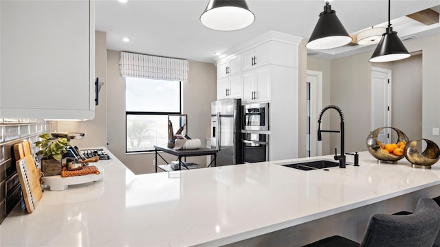 kitchen featuring a kitchen breakfast bar, appliances with stainless steel finishes, hanging light fixtures, white cabinets, and sink