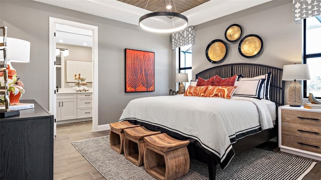 bedroom featuring wood ceiling, a raised ceiling, and ensuite bath