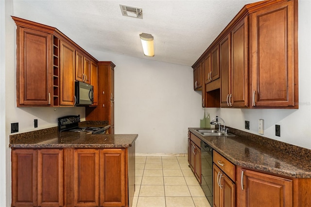 kitchen with dark stone countertops, sink, light tile patterned floors, and black appliances