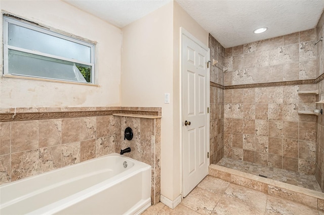 bathroom featuring a textured ceiling and tiled shower / bath