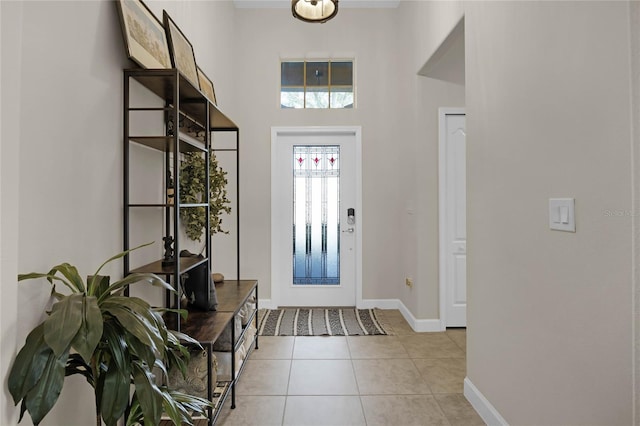 foyer entrance with light tile patterned floors and a towering ceiling