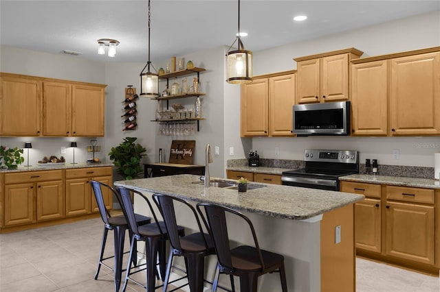 kitchen featuring a center island with sink, light stone countertops, sink, and appliances with stainless steel finishes