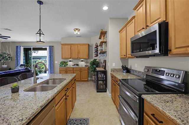 kitchen featuring decorative light fixtures, sink, light stone counters, and stainless steel appliances