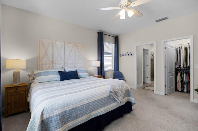 bedroom featuring a walk in closet, ceiling fan, a closet, and light carpet