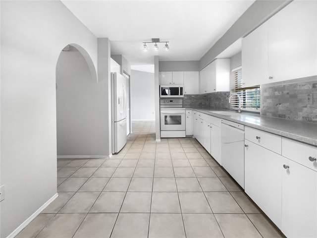 kitchen with sink, light tile patterned floors, backsplash, white appliances, and white cabinets