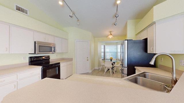 kitchen featuring white cabinetry, sink, vaulted ceiling, and appliances with stainless steel finishes