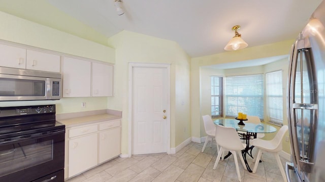 kitchen featuring white cabinets, light tile patterned flooring, lofted ceiling, and appliances with stainless steel finishes