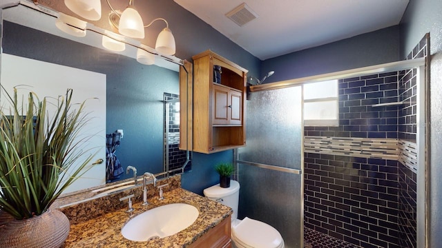 bathroom with vanity, a shower with shower door, and toilet