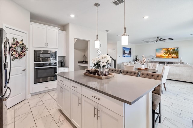 kitchen featuring white cabinets, pendant lighting, stainless steel appliances, and a kitchen island