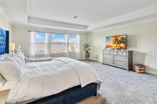 carpeted bedroom with ornamental molding and a tray ceiling