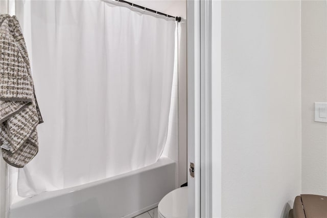 bathroom featuring toilet and shower / bathtub combination with curtain