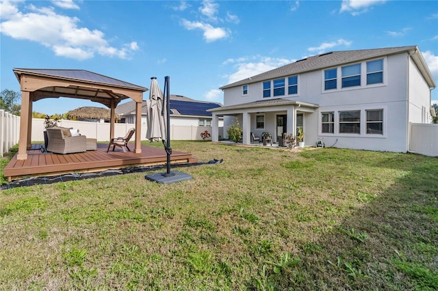 rear view of property featuring a gazebo, a lawn, and a wooden deck