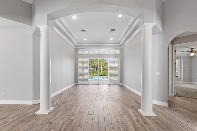 unfurnished living room with decorative columns, a healthy amount of sunlight, and light hardwood / wood-style flooring