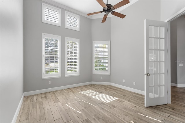 spare room featuring a high ceiling, ceiling fan, and light hardwood / wood-style flooring