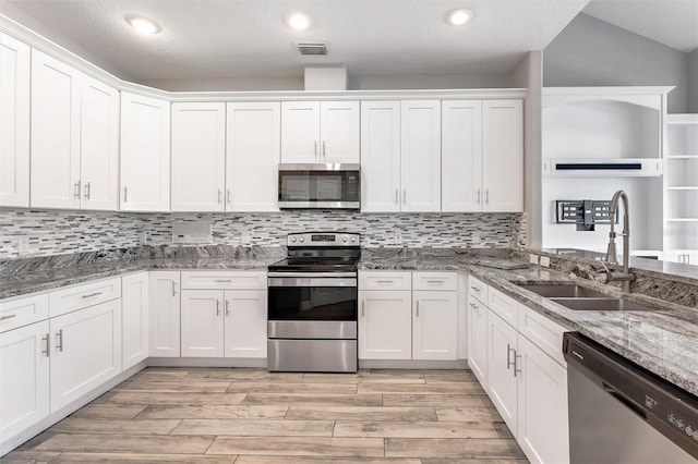 kitchen featuring stainless steel appliances, white cabinetry, sink, and stone countertops