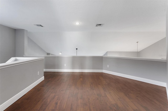 bonus room with dark hardwood / wood-style floors and vaulted ceiling