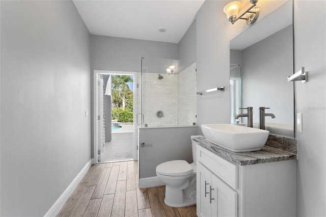 bathroom with hardwood / wood-style flooring, vanity, toilet, and a shower with shower door