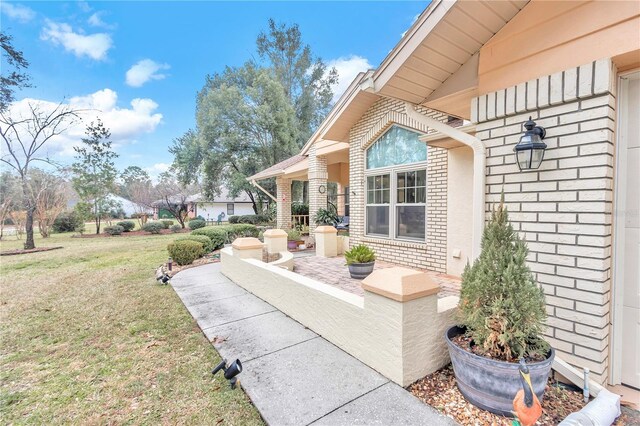 doorway to property featuring brick siding and a lawn