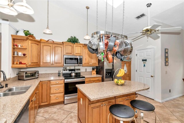 kitchen with ceiling fan, a center island, stainless steel appliances, a sink, and light tile patterned flooring