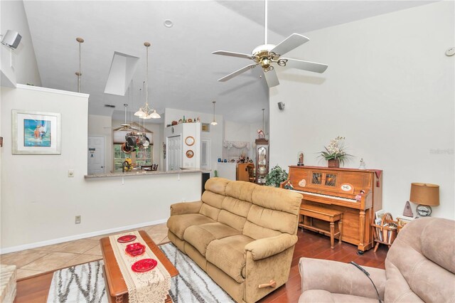 tiled living area with vaulted ceiling, ceiling fan, and baseboards