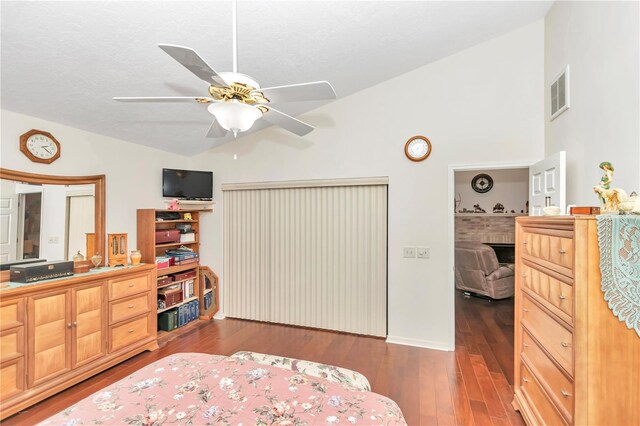 bedroom with lofted ceiling, ceiling fan, a fireplace, wood finished floors, and visible vents