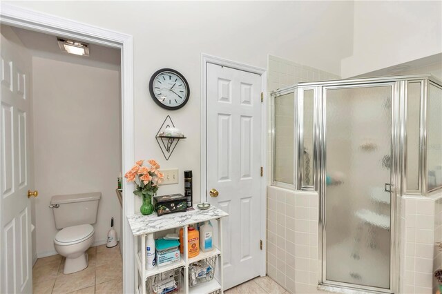 bathroom with a shower stall, toilet, and tile patterned floors