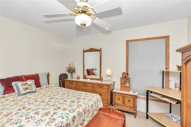 bedroom with ceiling fan, a textured ceiling, and light colored carpet