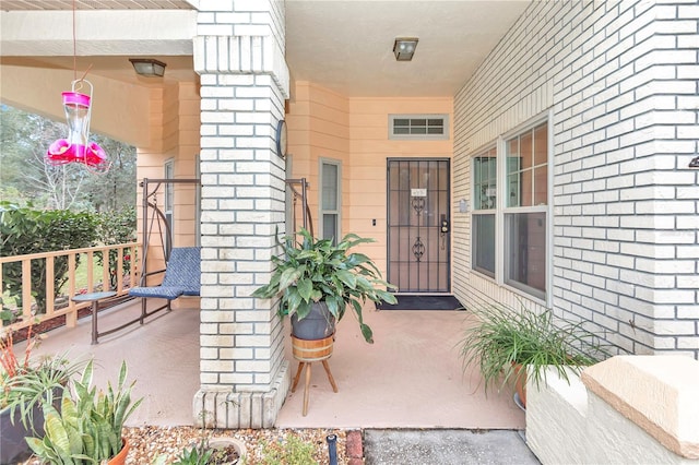 property entrance featuring covered porch and brick siding