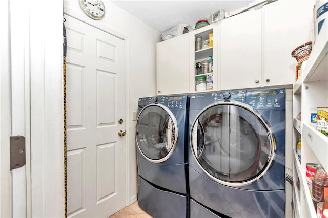 clothes washing area featuring light tile patterned floors, cabinet space, and separate washer and dryer