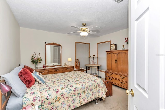 bedroom with a ceiling fan, light colored carpet, and a textured ceiling