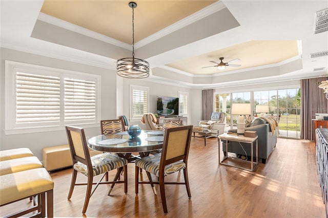 dining room with ceiling fan with notable chandelier, a raised ceiling, and crown molding