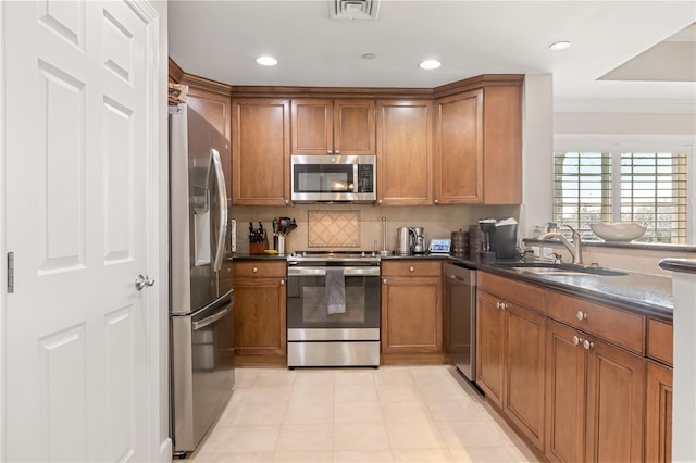 kitchen with decorative backsplash, crown molding, dark stone counters, appliances with stainless steel finishes, and sink