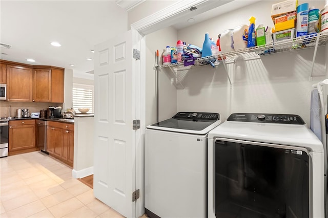 clothes washing area with sink, washer and clothes dryer, and light tile patterned floors