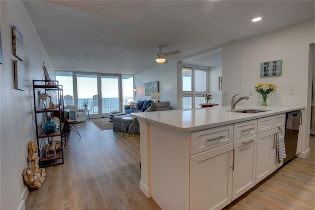 kitchen featuring ceiling fan, a wall of windows, black dishwasher, light hardwood / wood-style floors, and white cabinetry