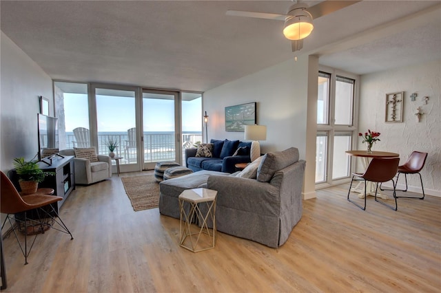 living room with light wood-type flooring, a wall of windows, and ceiling fan